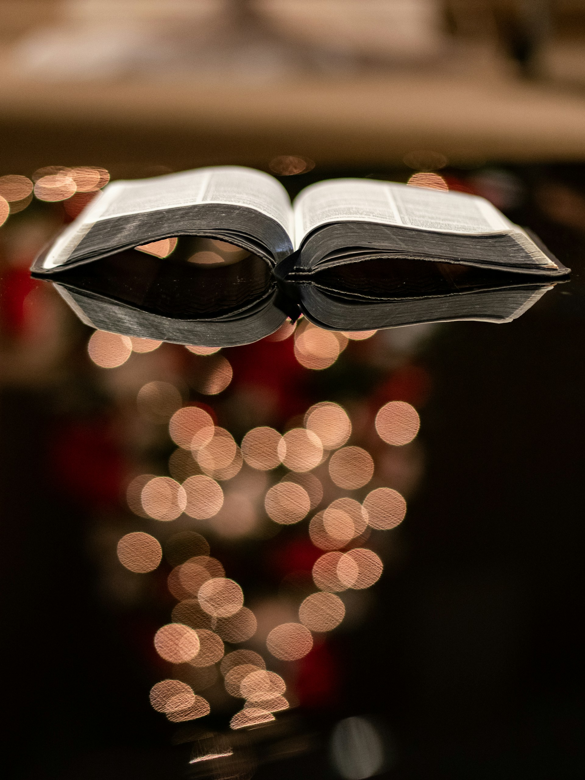 Open Bible resting on a wooden desk in warm light
